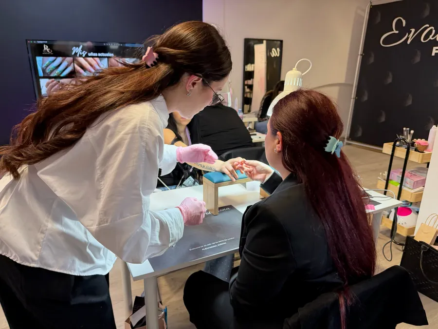 Prácticas en directo de manicura: una formadora guía a una asistente en el taller de Evoluciona